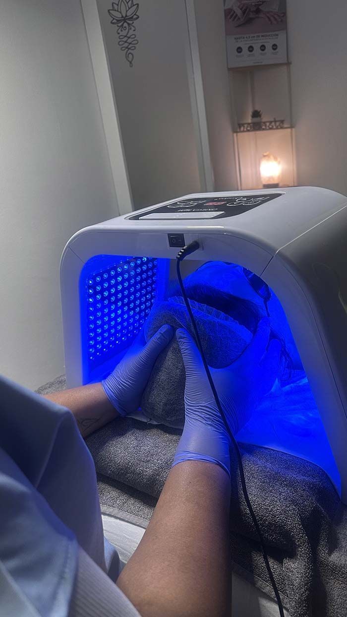 Manos en un secador de uñas con luz azul. Persona con guantes. Salón de belleza.