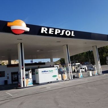 Marquesina de una gasolinera Repsol con surtidores y un depósito de AdBlue bajo un cielo azul despejado