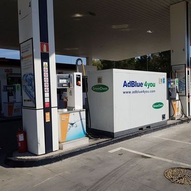 Estación de repostaje de AdBlue bajo una marquesina, con equipos blancos y azules en una zona de servicio junto a la carretera.
