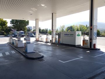 Estación de carga para vehículos eléctricos vacía, bajo una marquesina blanca, con postes de carga y plazas de aparcamiento