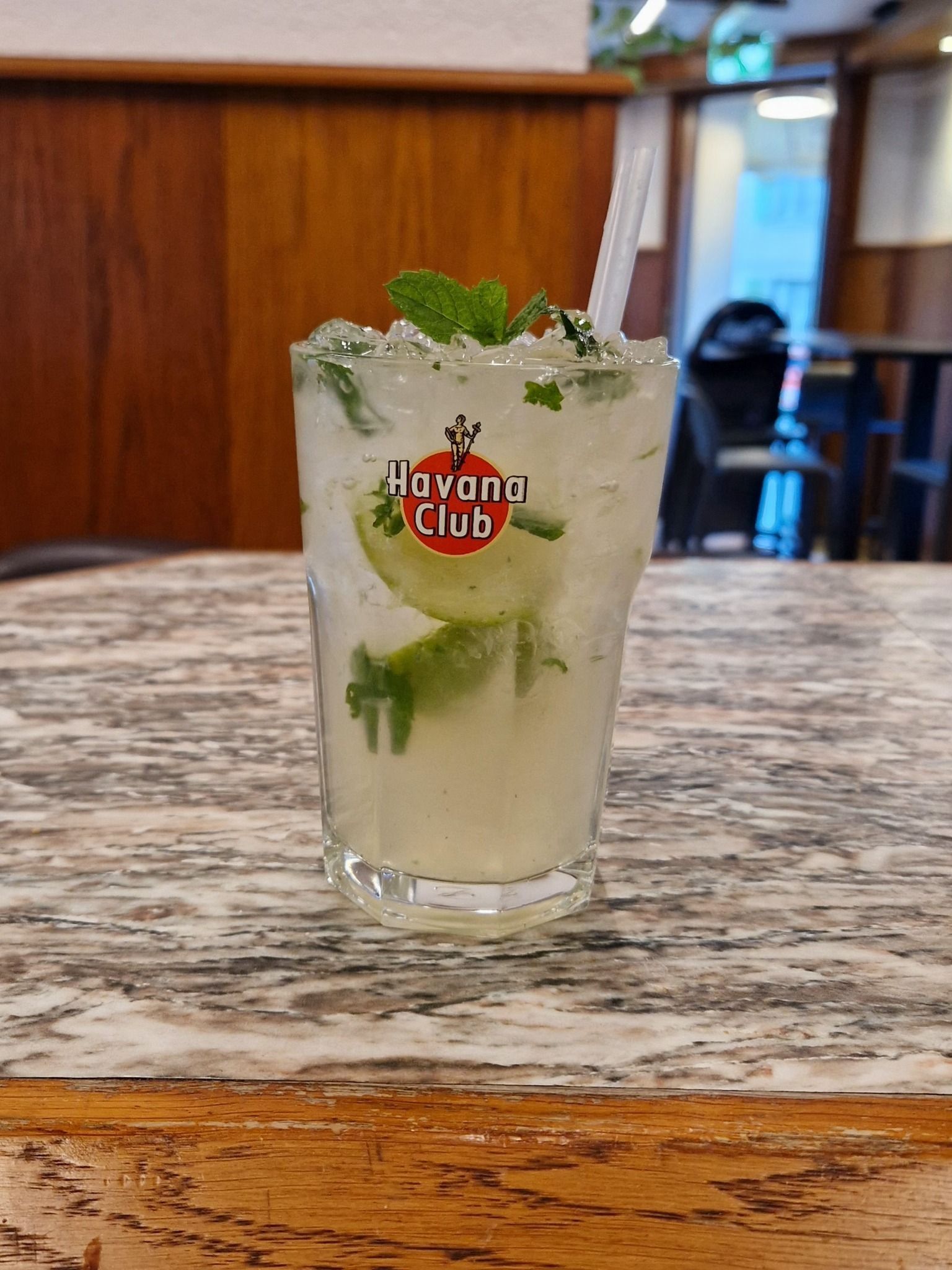 Cocktail Mojito dans un verre Havana Club, garni de menthe et de citron vert, sur une table en marbre.