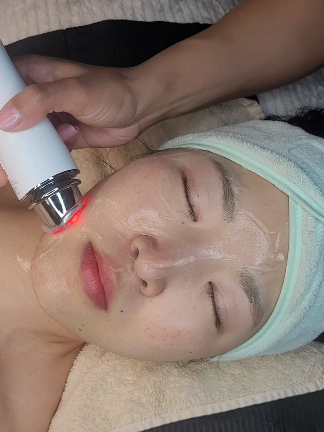 Una mujer con una toalla envuelta alrededor de su cabeza está recibiendo un tratamiento facial.