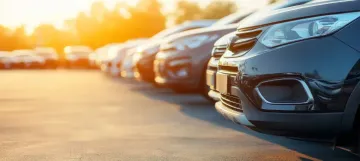 Coches aparcados en fila, iluminados por una cálida puesta de sol.