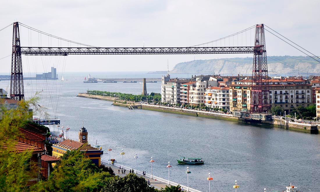 Puente colgante sobre un río, conectando edificios; Bilbao, España.