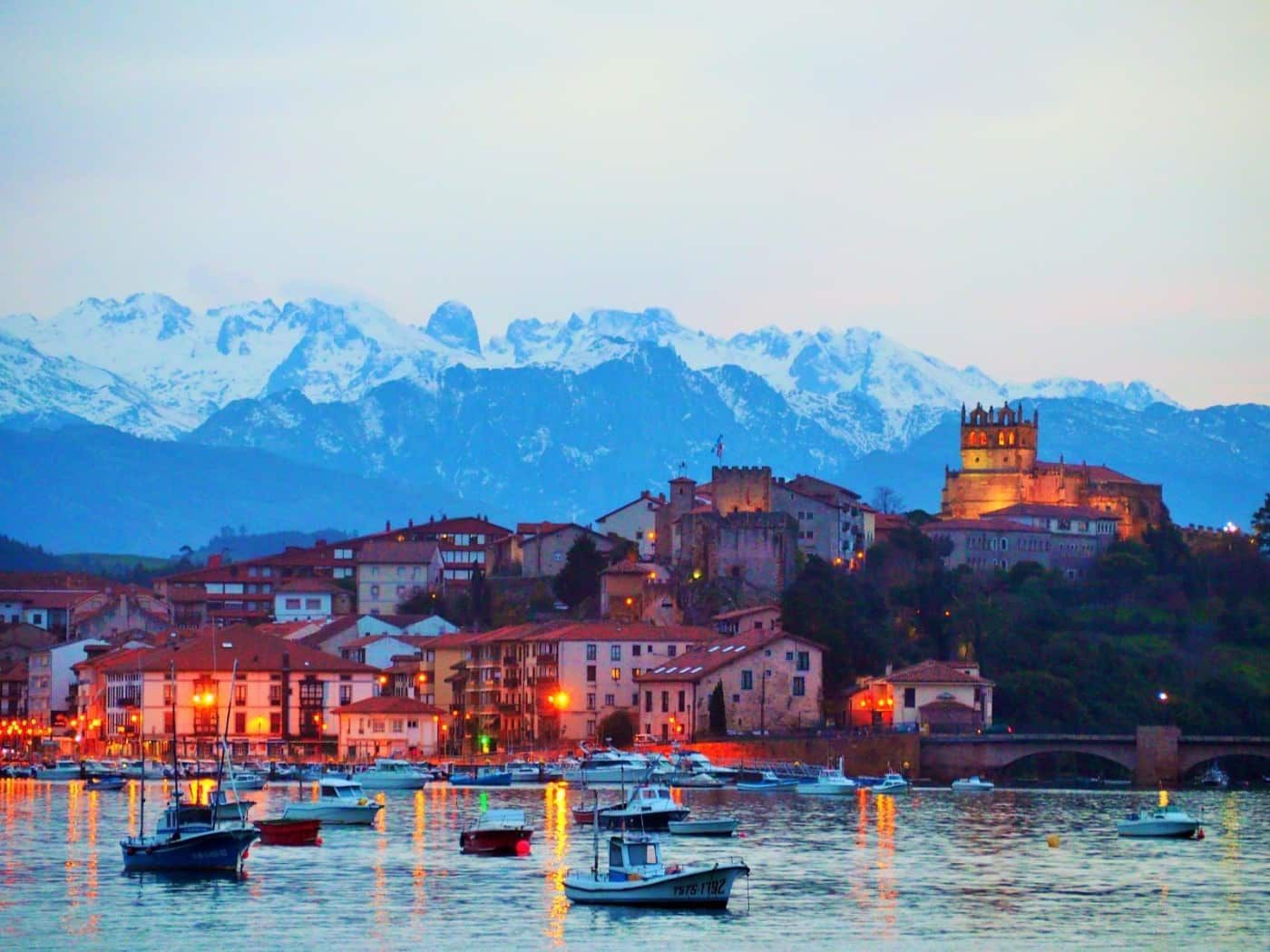 Camino sinuoso en una cresta costera rocosa y verde, que conecta con un mar oscuro y agitado bajo un cielo nublado.