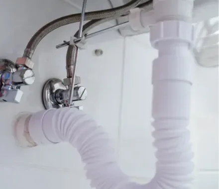 Un hombre está arreglando una tubería del lavabo de un baño.