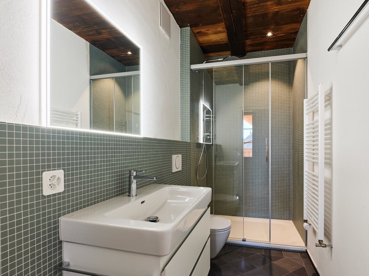 Ein Badezimmer mit Waschbecken, Spiegel und ebenerdiger Dusche.