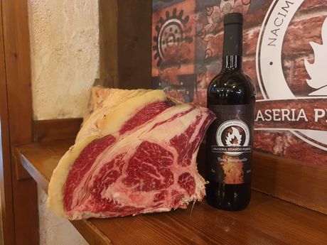 Una botella de vino junto a un trozo de carne