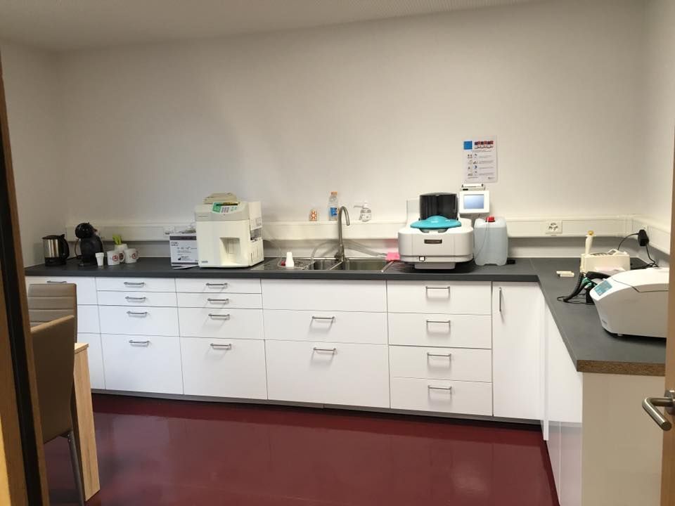 Une cuisine avec des armoires blanches et une imprimante sur le comptoir.