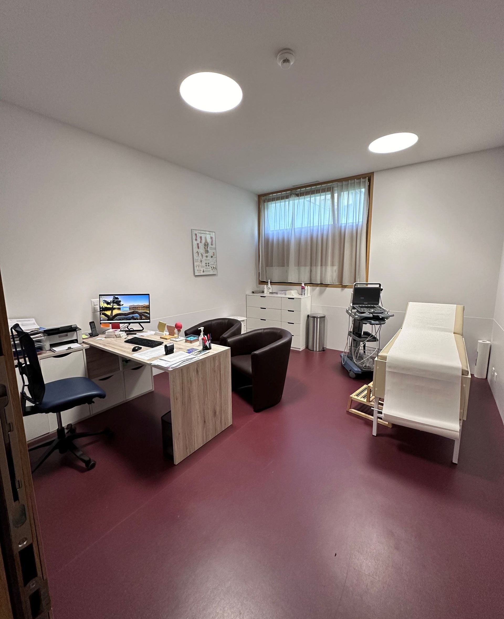 Un cabinet médical avec un bureau, des chaises et un lit.