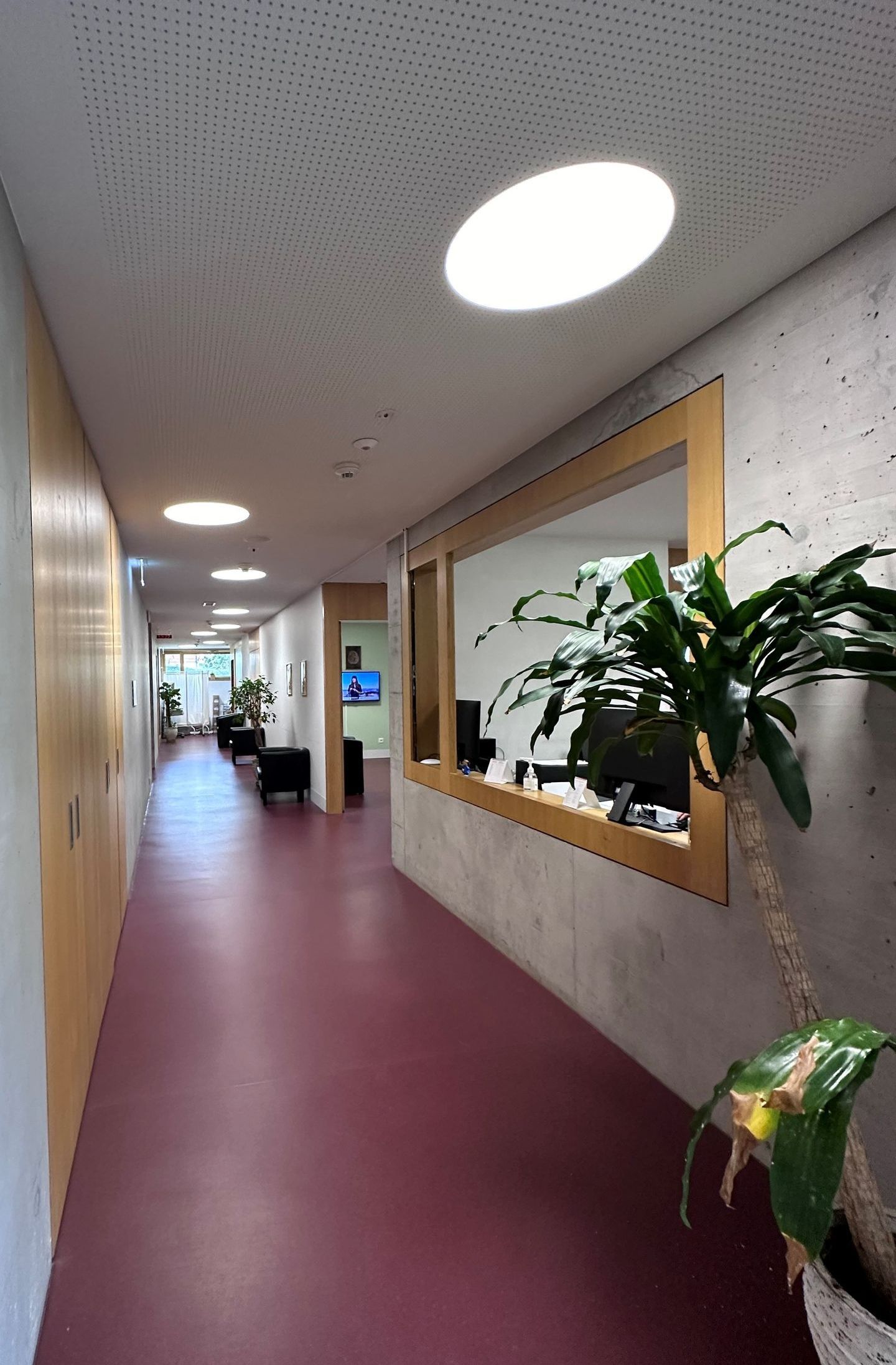 Un long couloir avec des sols rouges et un comptoir en bois