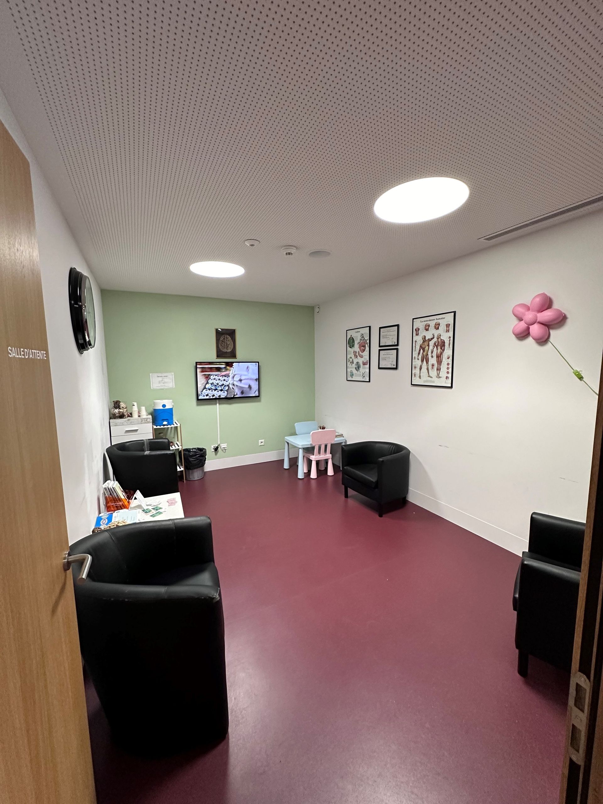 Une salle d'attente avec une table et des chaises et une télévision à écran plat