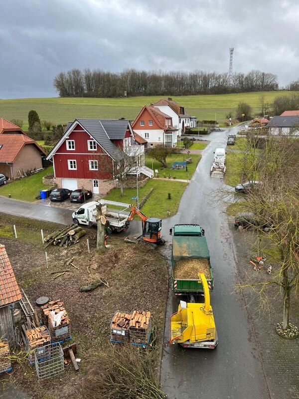 Ein gelber Lastwagen fährt eine Straße neben einem Haus entlang.