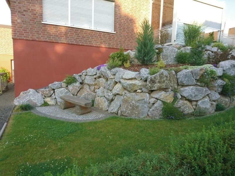 Eine Felswand mit einer Bank vor einem Haus