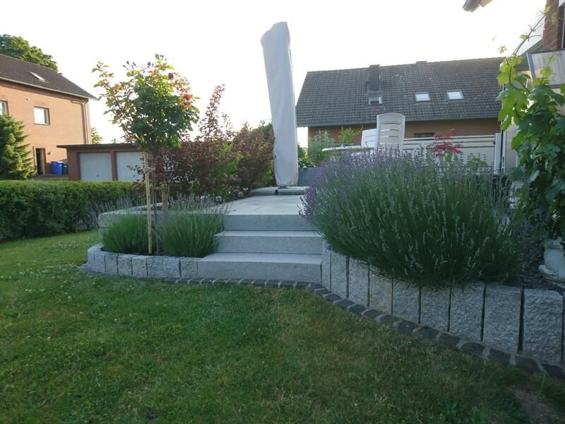 Ein Garten mit Treppen, die zu einer Statue hinaufführen, und einem Haus im Hintergrund