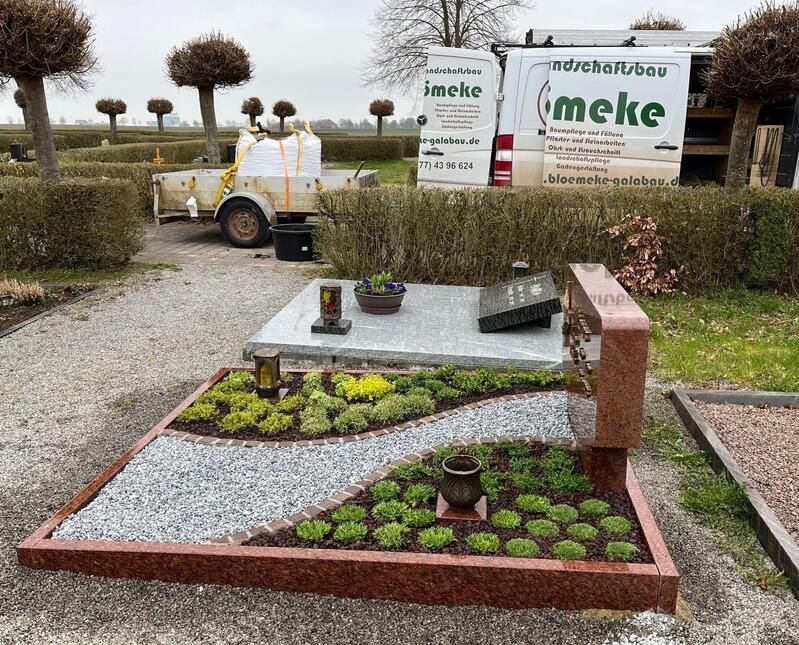 Ein weißer Lieferwagen mit dem Wort „Meke“ darauf steht vor einem Friedhof