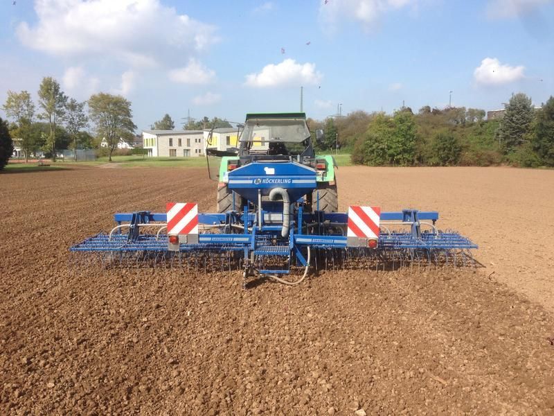 Ein blau-weißer Traktor pflügt ein Feld