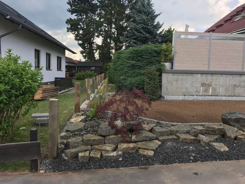Ein Haus mit einem Zaun und einer Steinmauer davor.