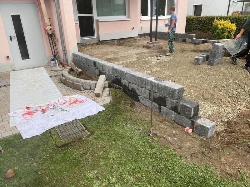 Vor einem Haus wird eine Ziegelmauer gebaut.