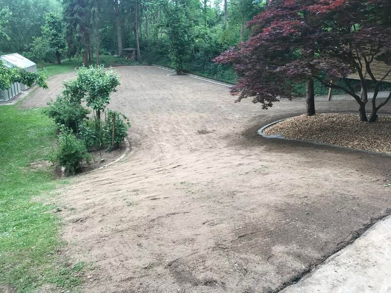 Eine unbefestigte Auffahrt führt zu einem Haus mit Bäumen im Hintergrund.