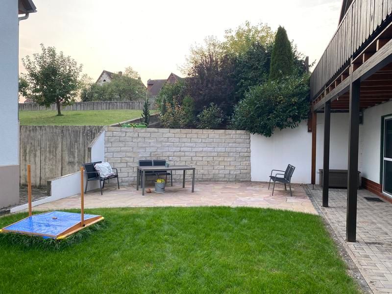 Ein Hinterhof mit Tisch und Stühlen und einem Sandkasten.