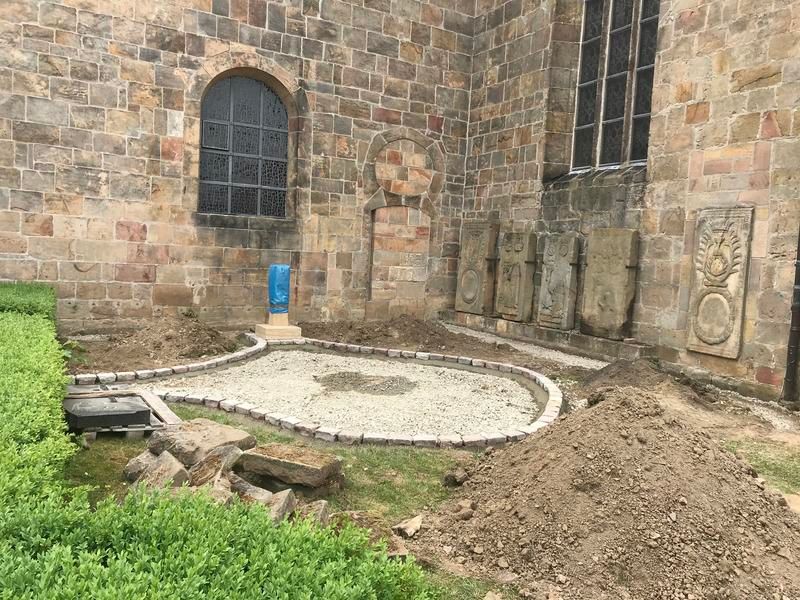 Vor einem Backsteingebäude liegt ein großer Erdhaufen.