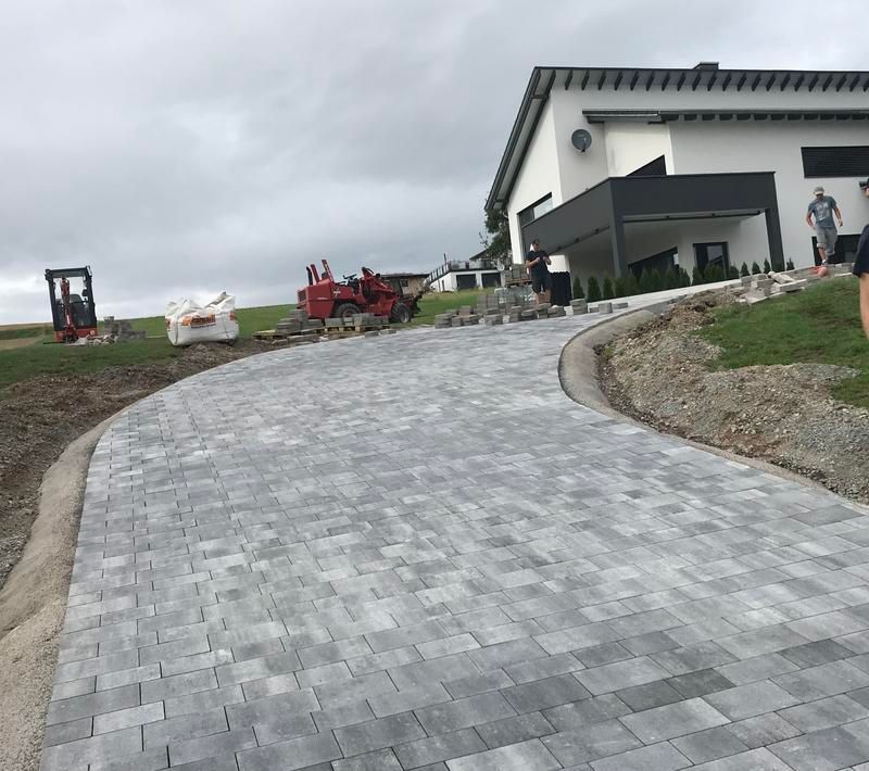 Vor einem Haus wird eine gepflasterte Auffahrt gebaut.