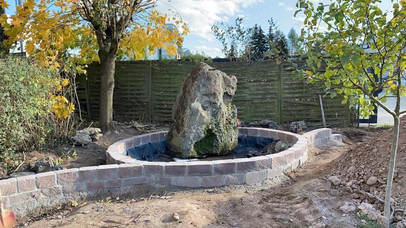 Ein großer Felsen liegt in der Mitte eines Teichs in einem Garten.