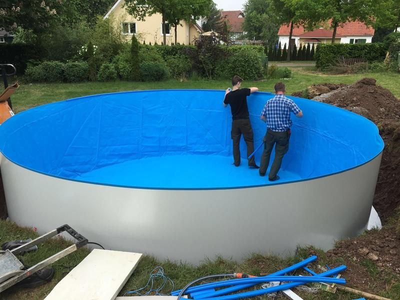 Zwei Männer arbeiten an einem Swimmingpool in einem Hinterhof.