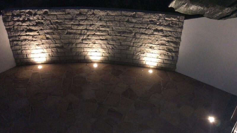 Ein Raum mit einer Ziegelwand und Lichtern auf dem Boden.