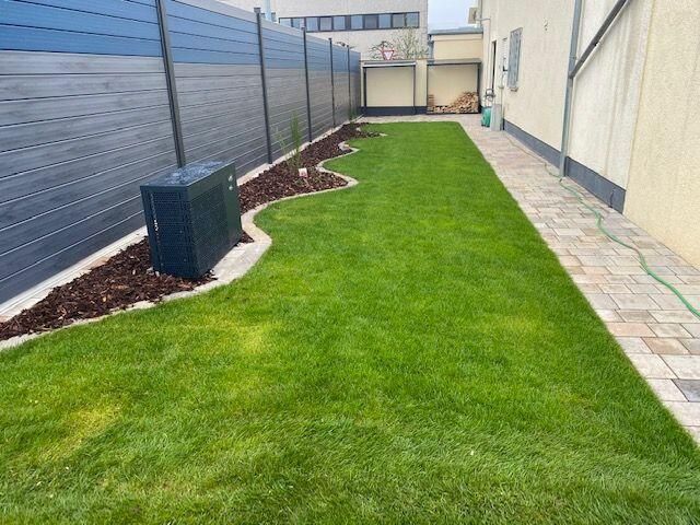 Ein Hinterhof mit Zaun und üppigem grünen Rasen.