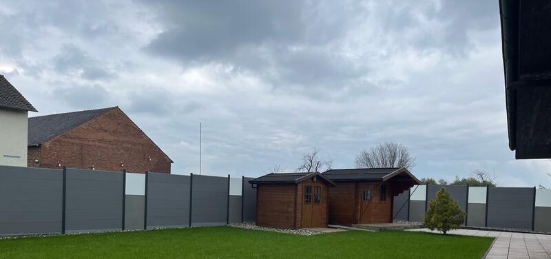 Ein Hinterhof mit einem Zaun und einem Haus im Hintergrund.
