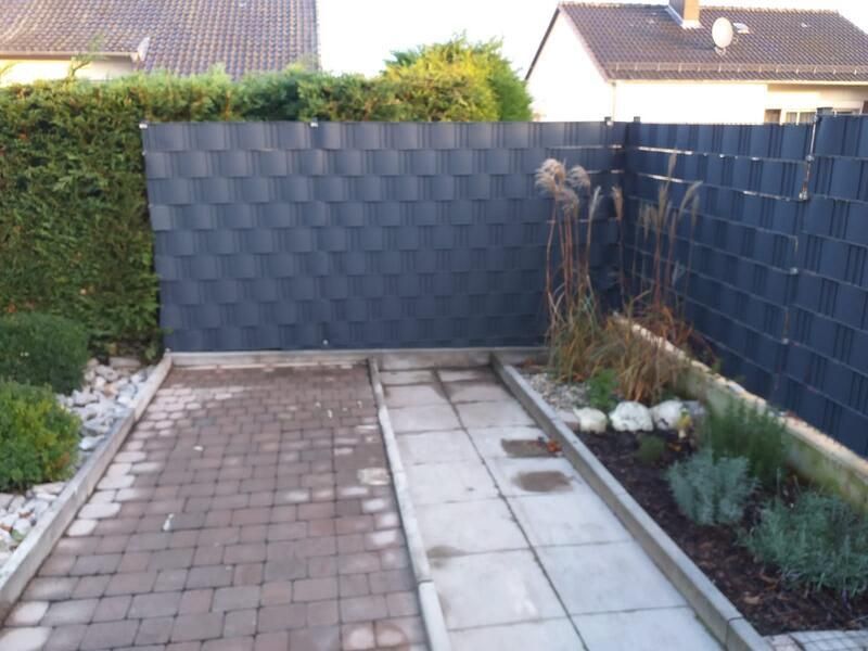 Ein Ziegelweg, der zu einem schwarzen Zaun führt