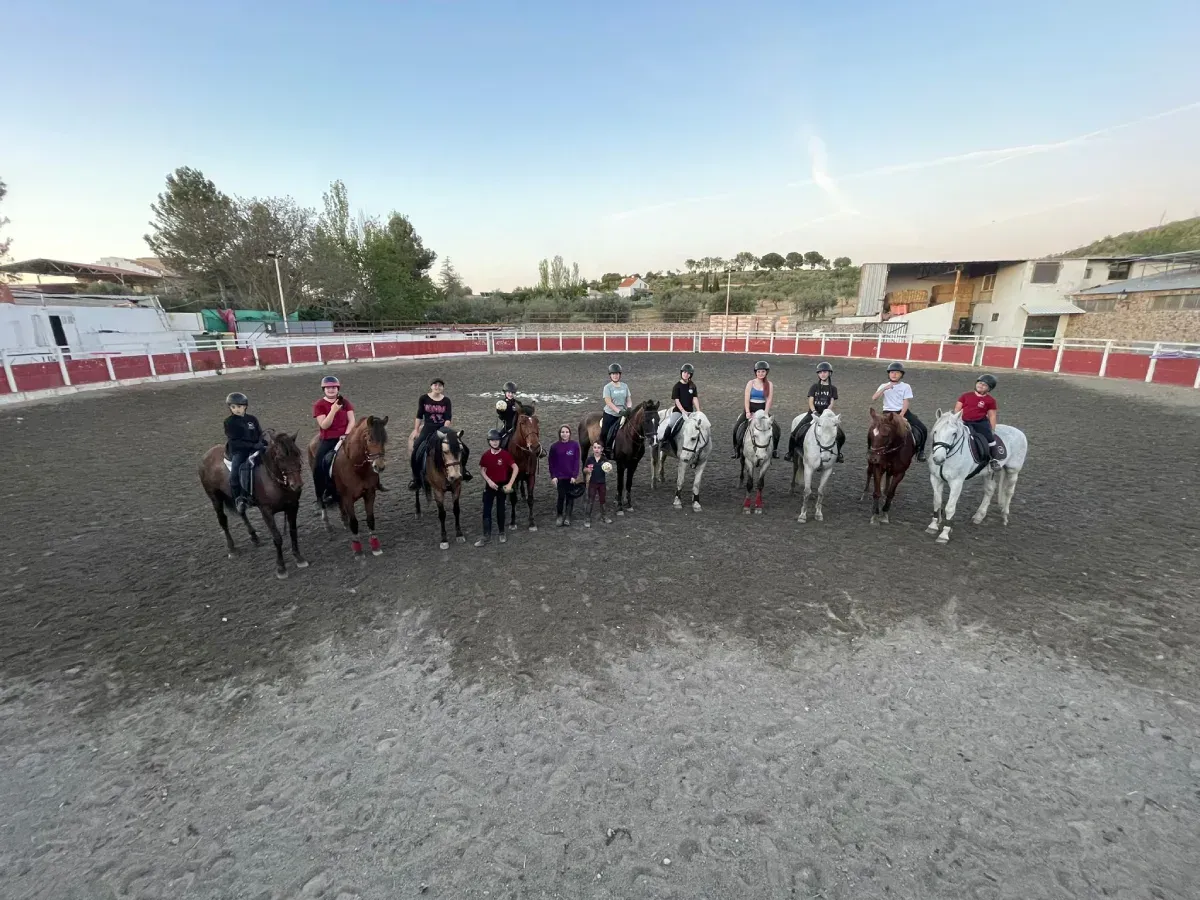 Grupo de personas a caballo en una plaza circular. Jinetes posan con caballos al aire libre.