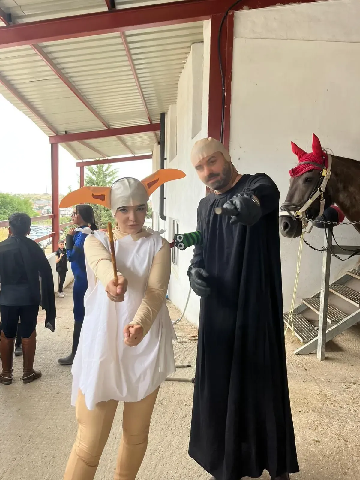 Dos personas disfrazadas posan junto a un caballo. Una vestida de extraterrestre con un bastón en la mano