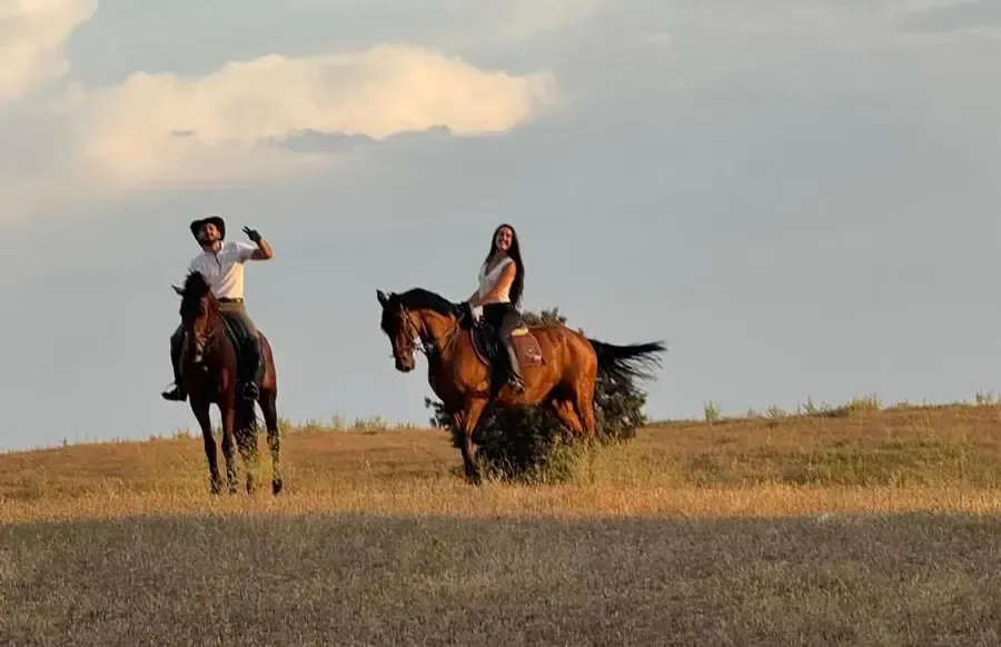 Tres jinetes a caballo en un campo nevado bajo un cielo azul.
