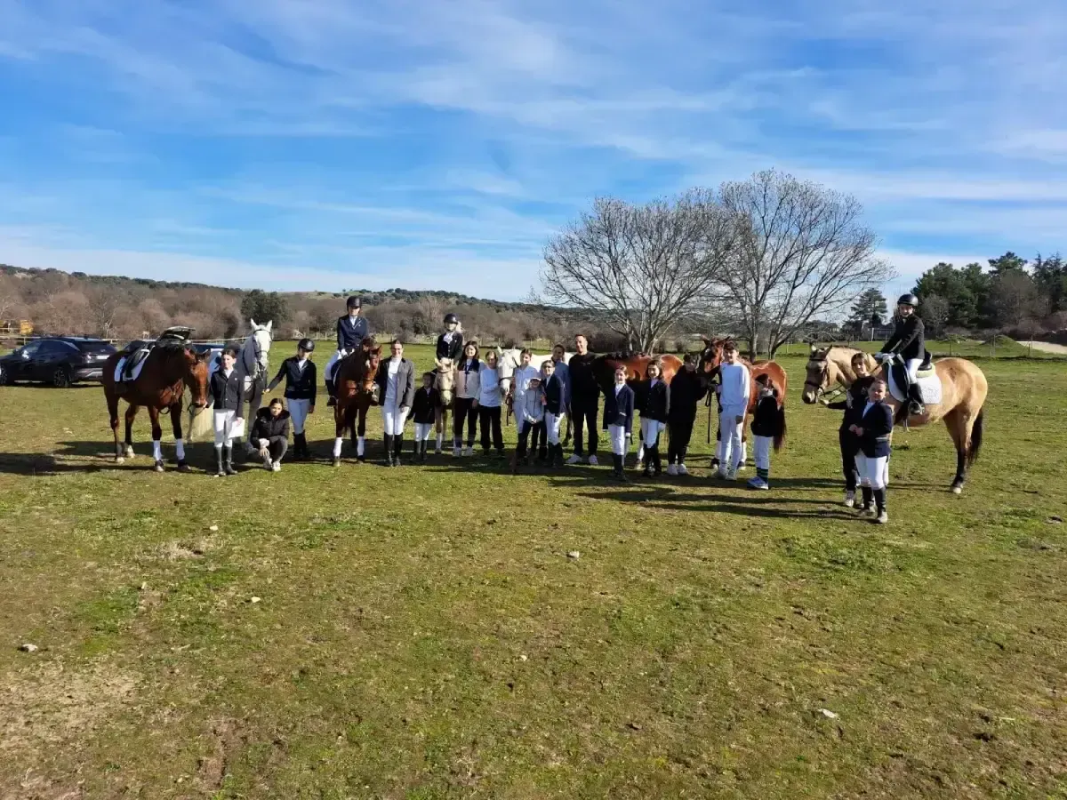 Grupo de personas con caballos en un campo en un día soleado. Jinetes y espectadores posan.