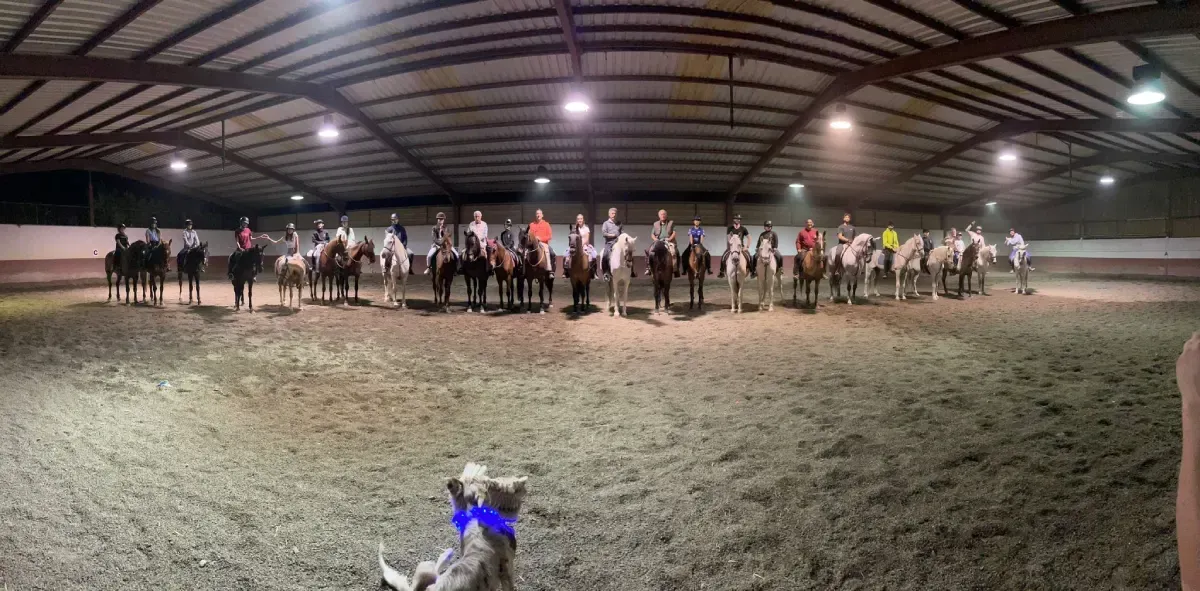 Grupo de personas a caballo dentro de una arena.