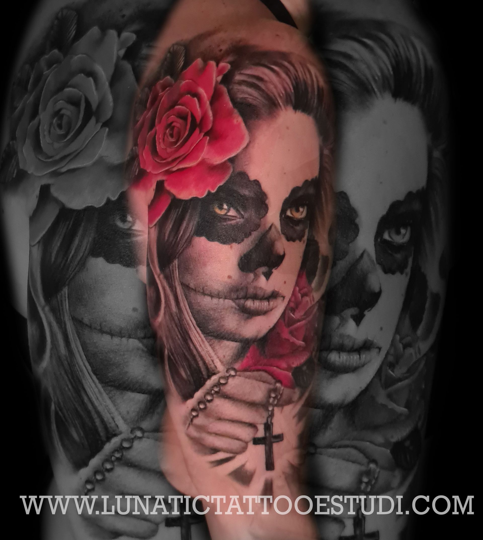 Un tatuaje en el antebrazo con el retrato de una persona con maquillaje facial que simula una calavera, una rosa roja y una cruz en una cadena de cuentas.