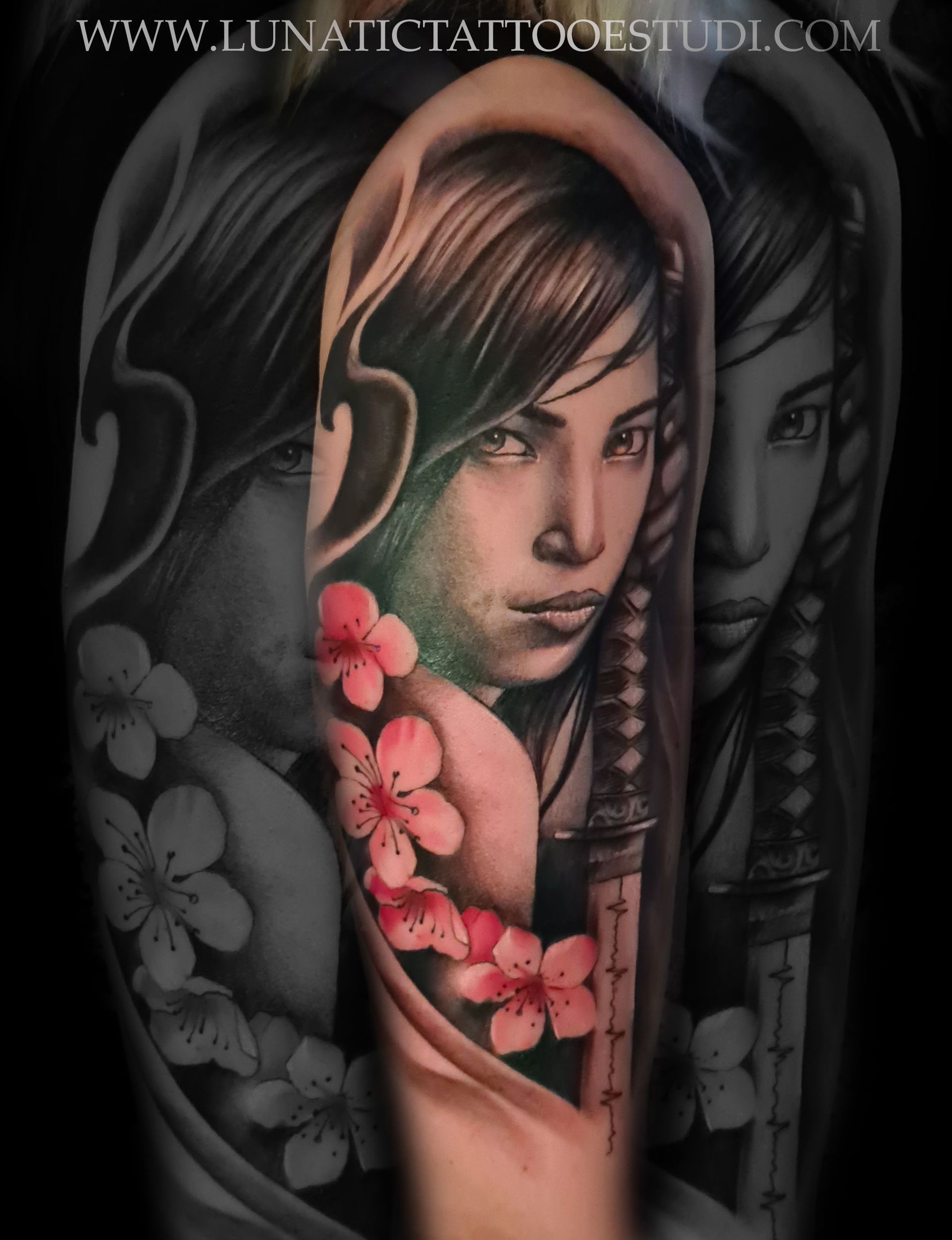 Un tatuaje realista de una persona con cabello oscuro, adornado con flores de cerezo rosas y la empuñadura de una espada sobre un fondo oscuro.