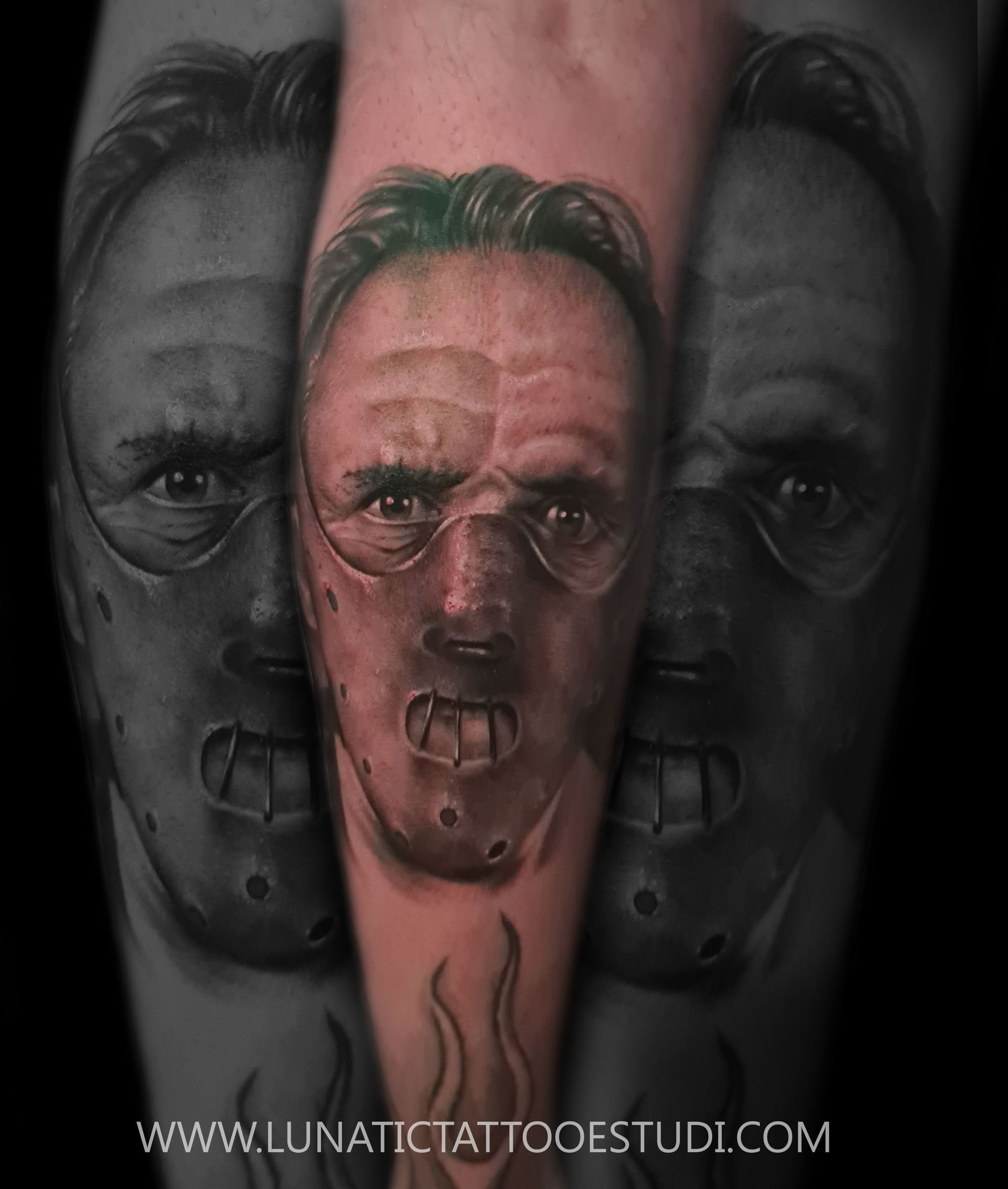Un tatuaje realista de Hannibal Lecter con su icónica máscara facial en un brazo.