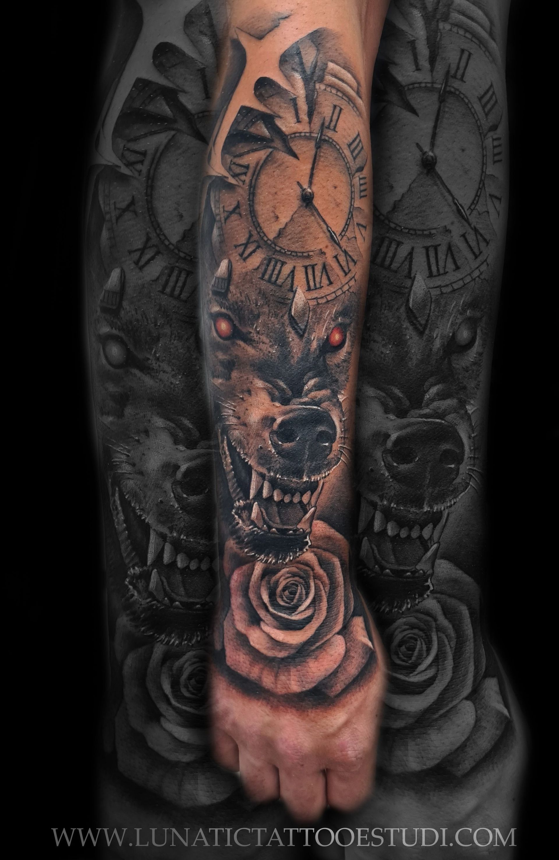 Tatuaje en el antebrazo en blanco y negro con un lobo gruñendo de ojos rojos, la esfera de un reloj y una rosa.