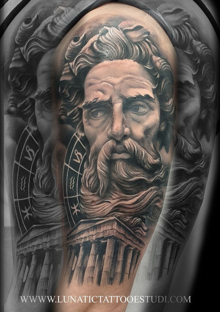 Un tatuaje en blanco y negro de una figura barbuda, un templo griego y una rueda astrológica en el hombro de una persona.