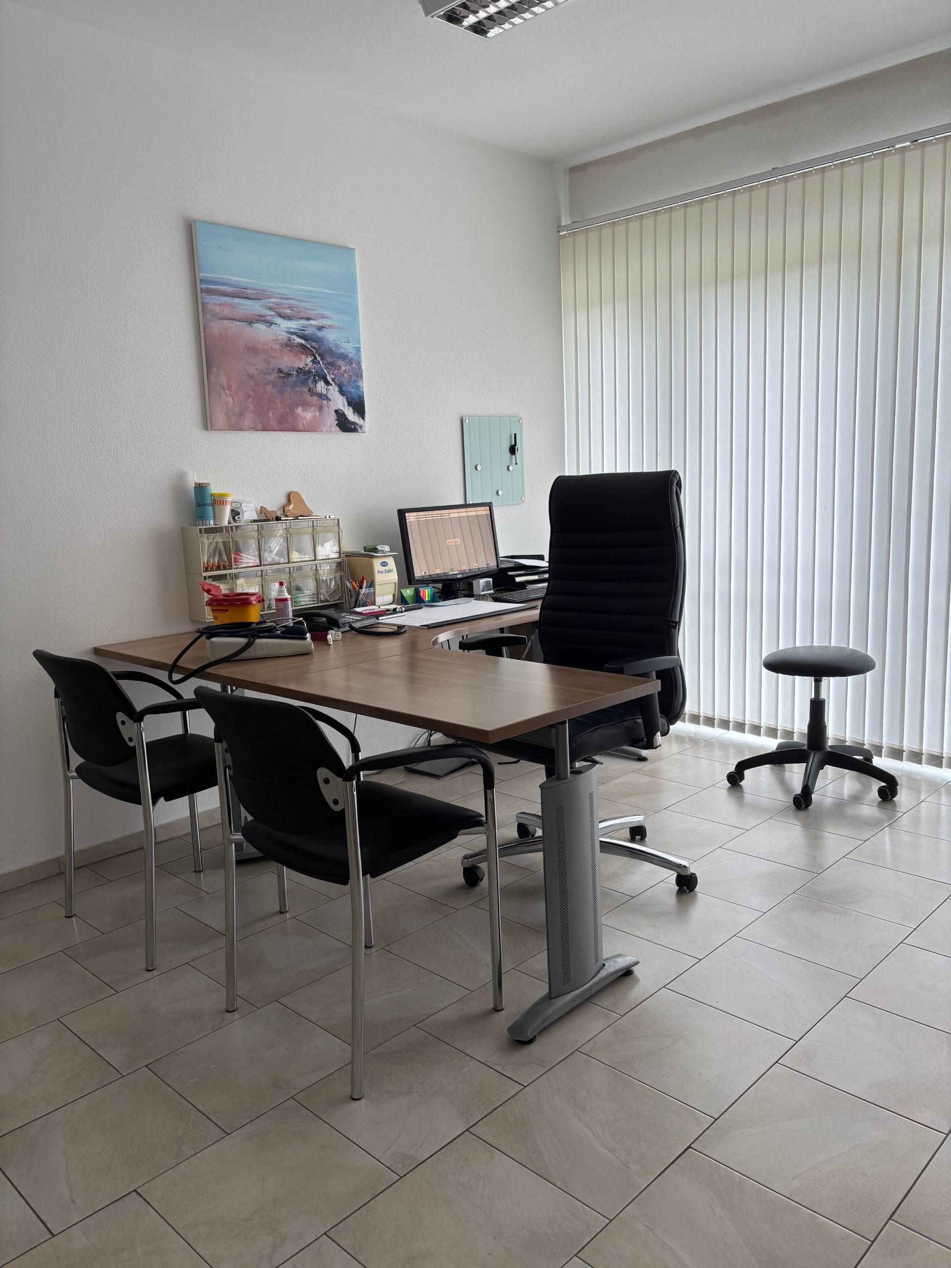 Untersuchungsraum mit Schreibtisch und zwei Besucherstühlen