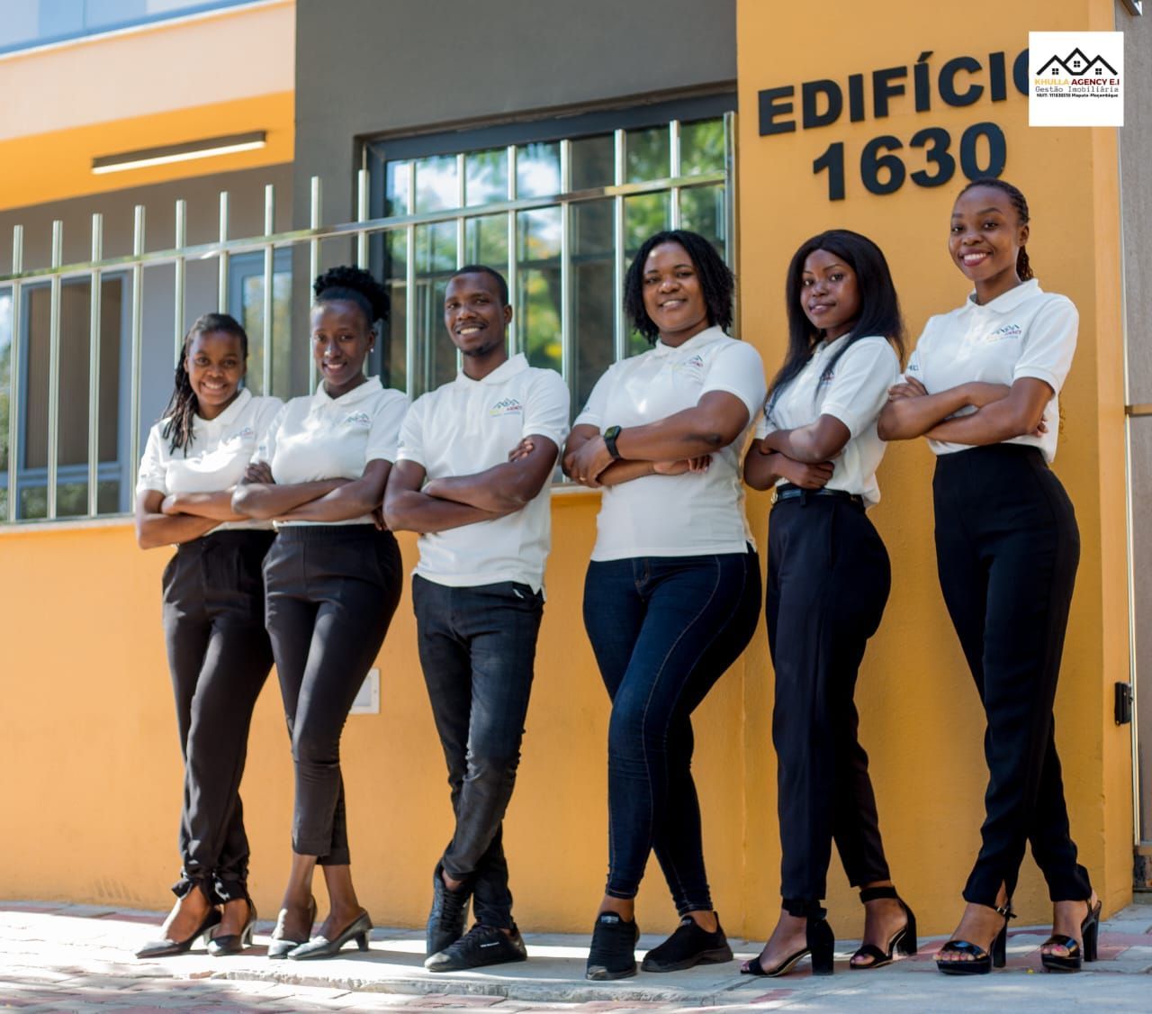 Group of six people, arms crossed, posing in front of a building with the number 1630.