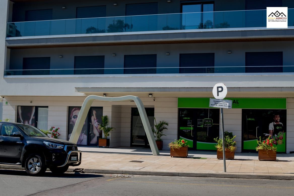 Exterior of modern building with parking sign, black car parked on street.