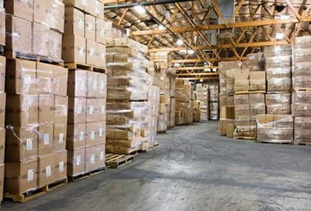Un gran almacén lleno de muchas cajas y paletas.