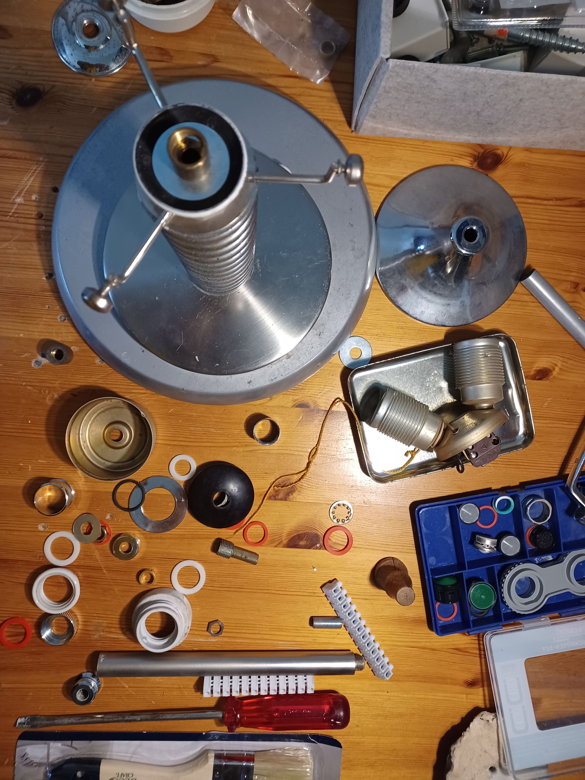 Verschiedene Metallmaschinenteile, Werkzeuge und Befestigungselemente lagen verstreut auf einer hölzernen Werkbank.