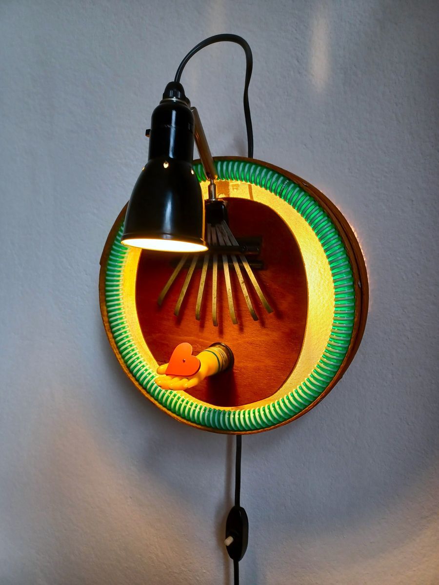 Bunte, runde Wandlampe mit schwarzem Schirm, die ein kleines Deko-Regal mit Vögeln darin beleuchtet.