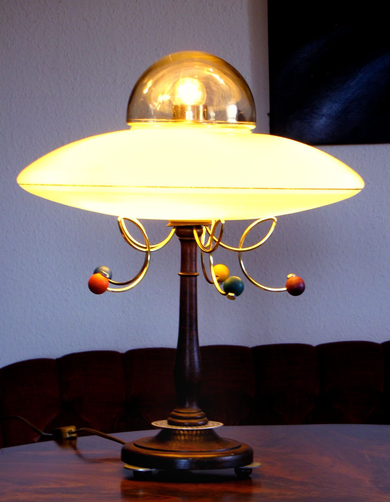 Dekorative Messing-Tischleuchte mit weißem Glasschirm und geschwungenen Fruchtverzierungen auf einem Holztisch
